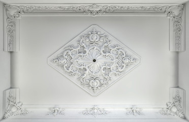 Decorative item made of white plaster on ceiling. Relief stucco interior