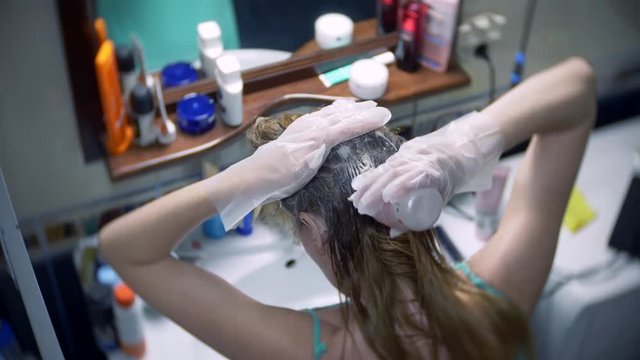 Woman colors her hair at home. Coloring hair close-up. 4k, slow motion