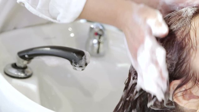 The hairdresser gently cleans hair with a shampoo in a beauty salon.