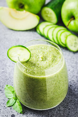 Fresh cucumber green apple smoothie in a glass on concrete background. Selective focus, copy space.
