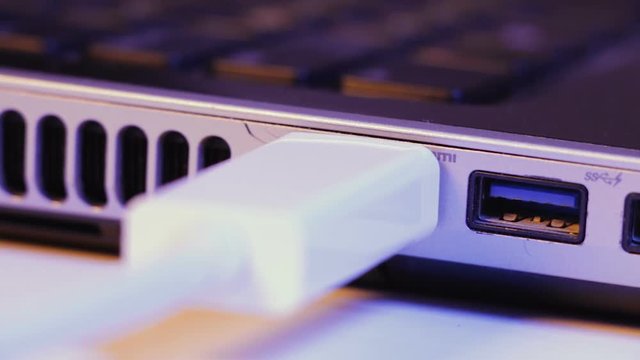 Closeup of HDMI cable plug inserted into port on the side of a laptop