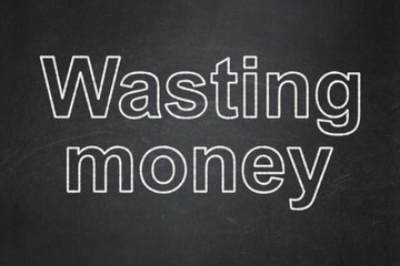 Obraz premium Currency concept: text Wasting Money on Black chalkboard background