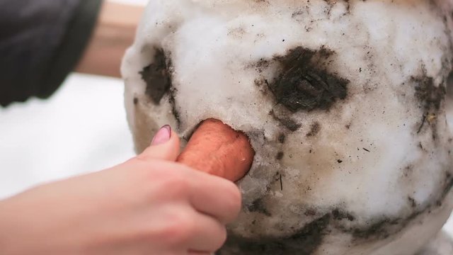 Woman without gloves inserts carrot snowman instead nose