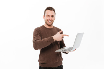 Smiling young man using laptop computer pointing.