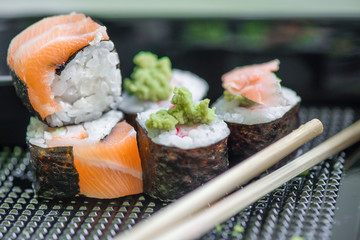 Fresh and delicious maki and nigiri sushi rolls with tiger shrimps, salmon, philadelphia cheese and wasabi served with soy sauce and ginger slices on black take away plate. Japanese food in restaurant