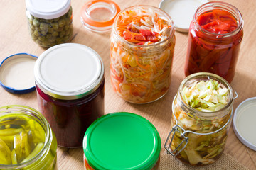 Fermented preserved vegetables in jar on wooden table. 