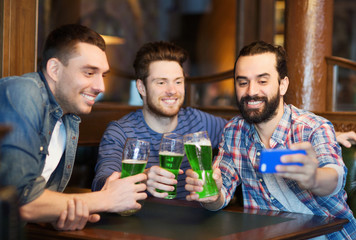 friends taking selfie with green beer at pub