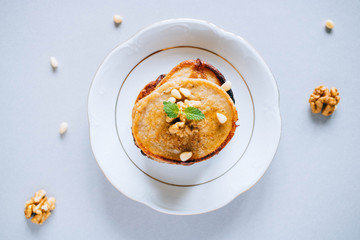 Banana pancakes with walnuts and cedar nuts, honey and mint, honey dipper on a white background, top view. Morning breakfast