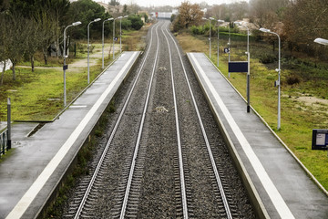 The railroad tracks stretch to the horizon and turn. Two ruts pass between the empty platforms of a small provincial station.