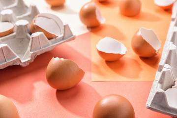 Eggs on geometric orange background. Broken egg shell on a pink paper. Pattern, easter concept. Carton box, tray