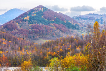 Romantic mountain landscape with naked and colorful trees around ancient village
