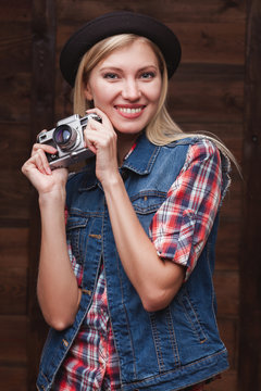 young smiling girl in black hat with vintage camera