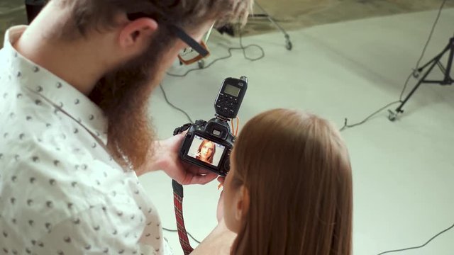 Photographer in a studio demonstrating photos to a model. Choosing proper photos.