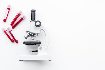 Blood analysis in clinacal lab. Test tubes near microscope on white background top view copy space