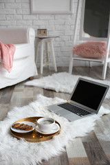 Tray with breakfast and laptop on fluffy carpet in room