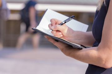 Fototapeta premium Closeup Of Beautiful Businesswoman Holding A Blank Note Book And Right With Luxury Pen Ready To Write.