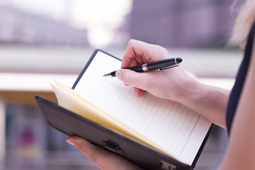 Obraz premium Closeup Of Beautiful Businesswoman Holding A Blank Note Book And Right With Luxury Pen Ready To Write.