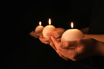 Young people with burning candles in darkness