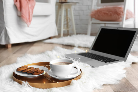 Tray with breakfast and laptop on fluffy carpet in room