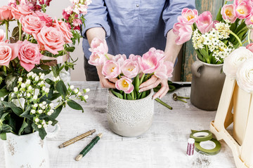 Florist at work: woman arranging flowers. Bouquet of pink tulips.