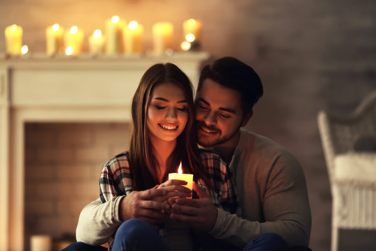 Happy young couple with burning candle at home