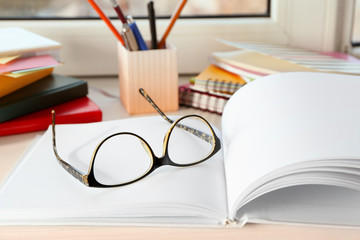 Glasses and notebook on windowsill indoors. Preparation for exam