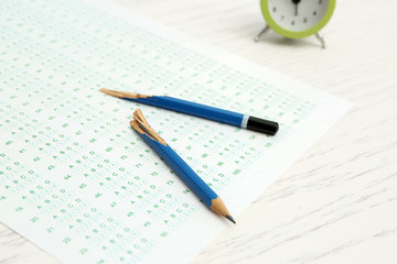 Broken pencil and test sheet on table, closeup. Preparation for exam