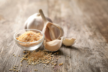 Bowl with granulated dried garlic on wooden background