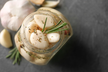 Fototapeta na wymiar Preserved garlic in glass jar on grey background