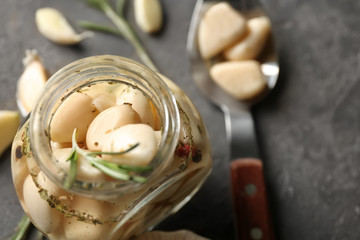 Fototapeta na wymiar Preserved garlic in glass jar on grey background