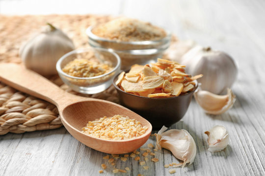 Spoon with granulated dried garlic on wooden background