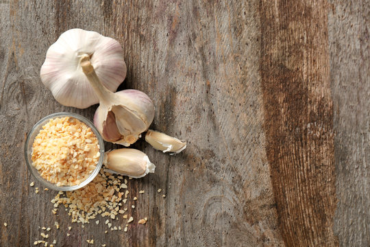 Bowl with granulated dried garlic on wooden background