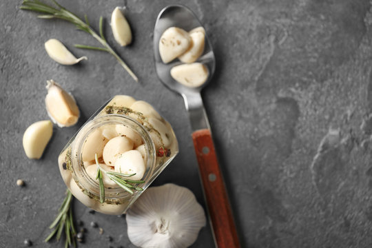 Preserved garlic in glass jar on grey background