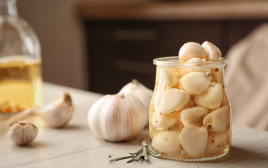 Preserved garlic in glass jar on table