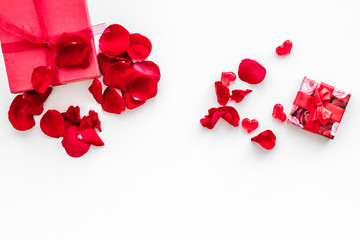 Gift for Valentine's day. Red gift box near red rose petals on white background top view copy space