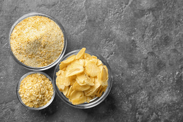 Dried garlic flakes, granules and powder in glass bowls on grey background