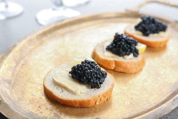 Tasty sandwiches with black caviar on metal tray