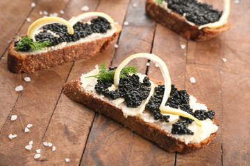 Tasty sandwiches with black caviar on table