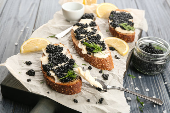 Tasty sandwiches with black caviar on table
