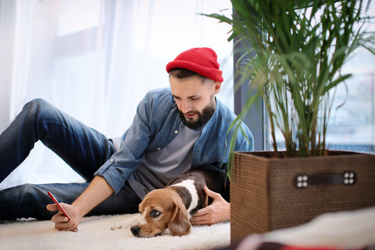 Handsome young hipster with dog at home