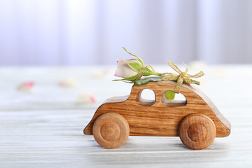Decorative wooden car with beautiful rose on table