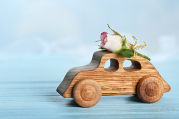 Decorative wooden car with beautiful rose on table