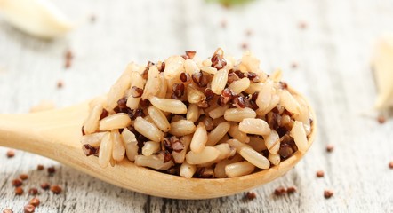 Cooked Quinoa brown rice in a wooden spoon on rustic white background, selective focus