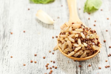Cooked Quinoa brown rice in a wooden spoon on rustic white background, selective focus