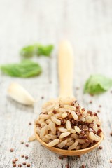 Cooked Quinoa brown rice in a wooden spoon on rustic white background, selective focus