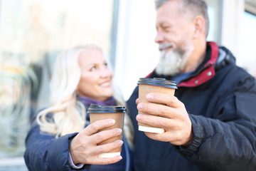 Happy mature couple drinking coffee outdoors on autumn day