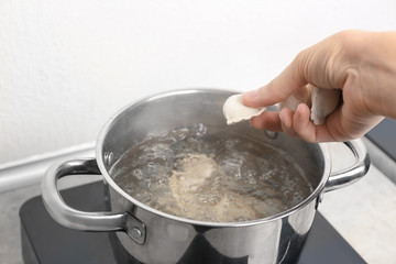 Woman cooking dumplings in boiling water, closeup