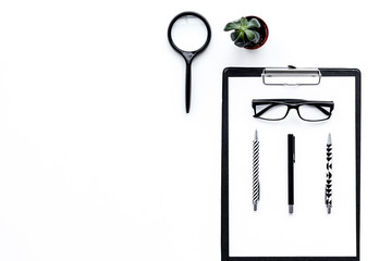 Strict work desk pattern with pad, glasses, magnifiger, cactus on white background top view copy space