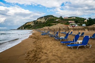 Fototapeta na wymiar Sand beach, loungers and umbrellas on the shore of Ionian sea, Corfu, Greece.