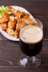Glass of dark beer and siracha buffalo chicken wings. Ale and food